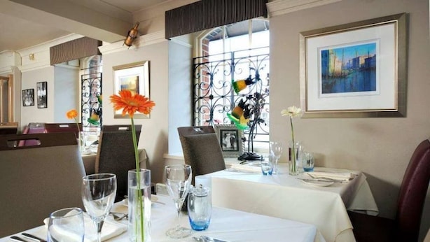 A dining area with tables set for two, featuring clear glassware and floral centerpieces. - Ennios Boutique Hotel (Southampton)