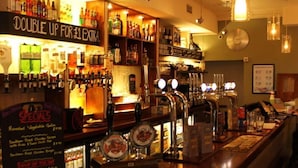 Eine Bar mit Flaschenregalen, einem Schild mit Sonderangeboten und einer Uhr an der Wand.