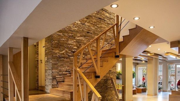 Un escalier en bois, avec un mur de pierre en arrière-plan, menant à l’étage supérieur.