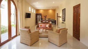 A spacious living area with a sofa set, wicker chairs, a coffee table, and a kitchen in the background. - Paraiso Granada (Granada)