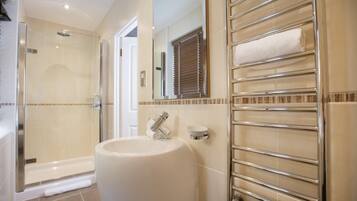 A bathroom with a glass-enclosed shower, a sink with a towel holder, and a mirror.
