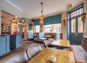 Un restaurant à l’ambiance chaleureuse, avec un bar, des tables et une horloge bien visible.