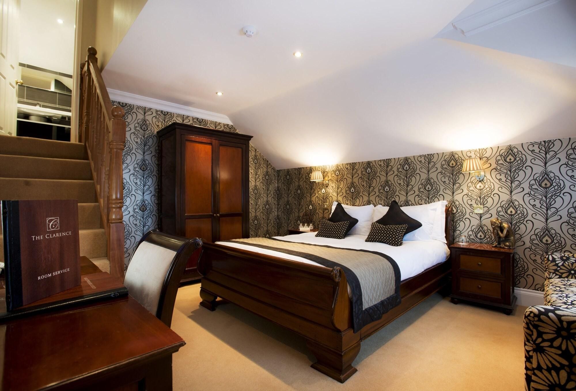 A bedroom with a wooden bed, a nightstand, a chair, a wardrobe, and a staircase.