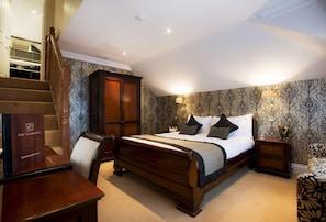 Une chambre à coucher avec un lit en bois, une table de chevet, une chaise, une armoire et un escalier.