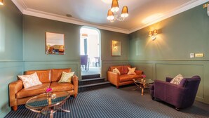 A hotel lobby with leather sofas, a glass coffee table, and a purple armchair. - The Clarence (Portsmouth)