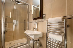 A modern bathroom with a glass-enclosed shower, a white sink, and a towel rack. - The Clarence (Portsmouth)