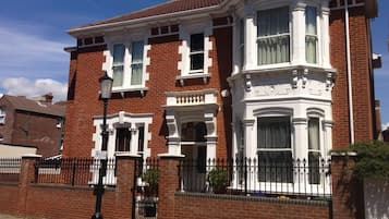 A two-story brick house with a bay window and a white decorative front.