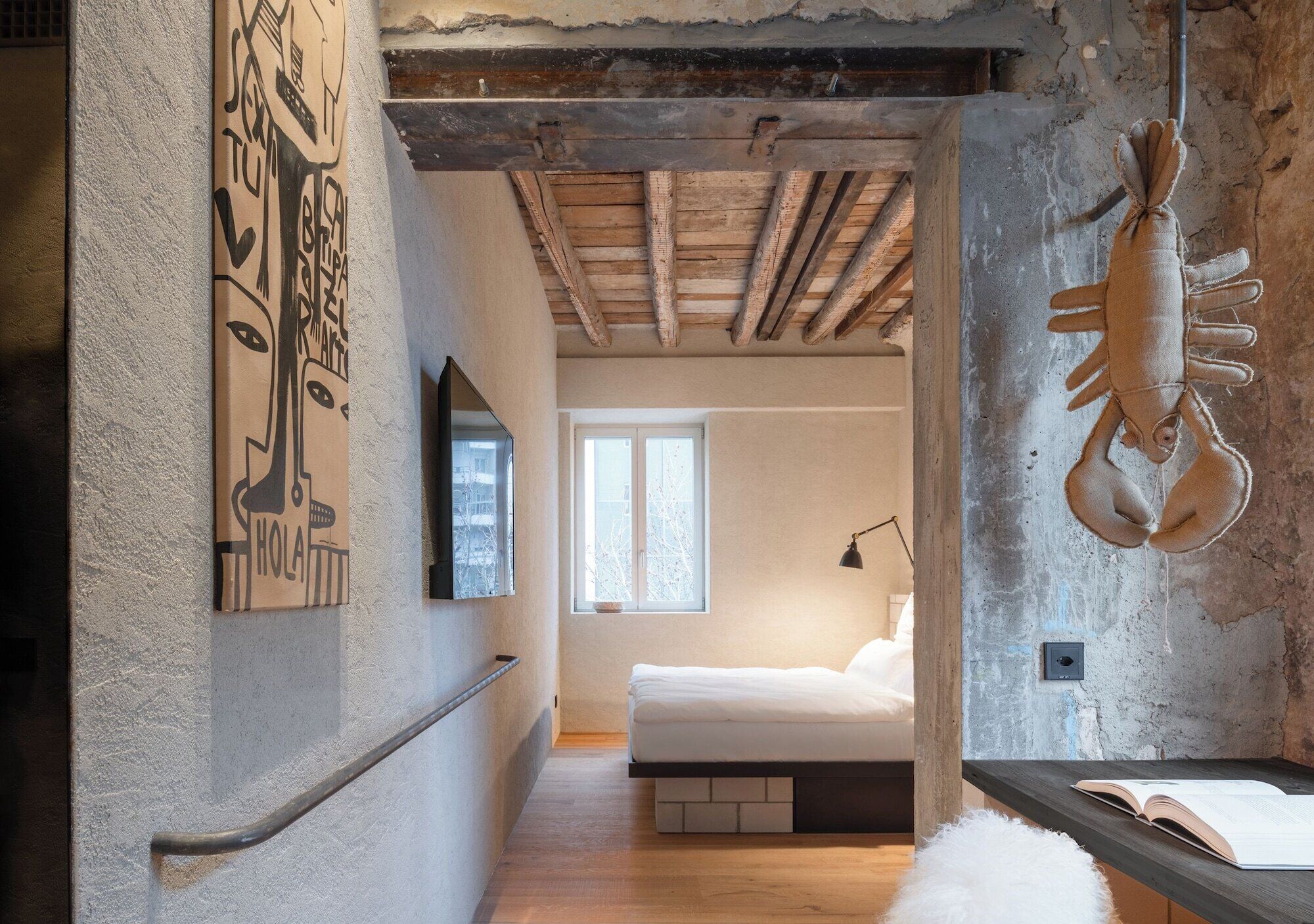 A bedroom with a bed, a window, a wall-mounted lamp, and a lobster decoration.