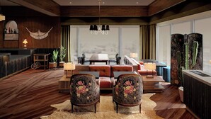 Un hall d’hôtel moderne avec un plancher en bois, un espace salon avec des canapés et des fauteuils, un comptoir d’accueil et une grande fenêtre avec des rideaux.