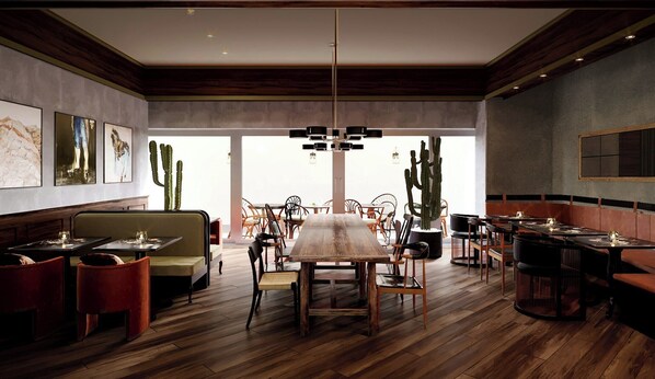 A restaurant interior with wooden flooring, a central dining table, multiple chairs, and cacti as decor. - Life House Lower Highlands (Denver)