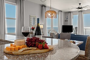 Ein Hotelzimmer mit Essbereich, ausgestattet mit einer Marmorplatte, einer Weinflasche, einem Weinglas, Käse, Trauben und Erdbeeren.