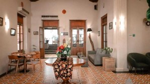 A spacious lobby with a round table, a sofa, and a staircase leading to an upper floor. - Solia Hotel Yosodipuro Solo (Surakarta)