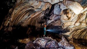 A person standing in a cave with large rock formations. - ARK Hotel Batu Caves (Batu Caves)