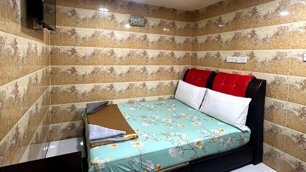 A bedroom with a floral bedspread, a black headboard, and a red and white pillow. - ARK Hotel Batu Caves (Batu Caves)