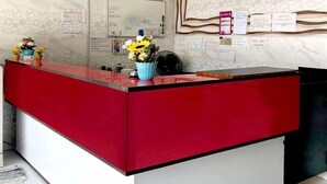 A reception desk with a red and white color scheme, a whiteboard, and various notices on the wall. - ARK Hotel Batu Caves (Batu Caves)