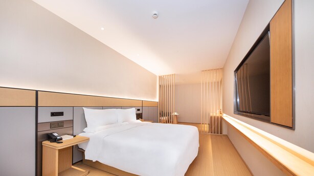 A modern hotel room with a large bed, bedside table, and a TV mounted on the wall. - JI Hotel Shanghai Anting Metro Station (Shanghai)