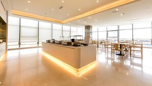 A modern hotel lobby with a central island counter, large windows, and a spacious seating area. - JI Hotel Shanghai Anting Metro Station (Shanghai)