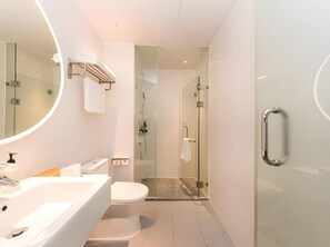 Ein modernes Badezimmer mit großem Spiegel, Toilette, Waschbecken und Duschbereich.