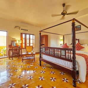 A four-poster bed with a ceiling fan, a dining area with chairs and a table, and a large window with a view. - Villa Du Ocean (Puducherry)