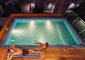 A rectangular pool with clear water, surrounded by a tiled deck and a wooden floor. - Villa Du Ocean (Puducherry)