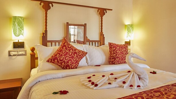 A bed with a canopy, decorative pillows, and a swan towel arrangement. - Villa Du Ocean (Puducherry)