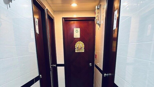 A hallway with white and black tiled walls and a wooden door at the end. - New Cosmos Hotel (Kowloon)