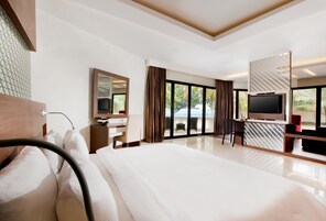 Habitación de hotel moderna con una cama grande, un escritorio con computadora, un televisor y un balcón con vista al exterior.