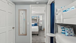 Ein Hotelzimmer mit einem Etagenbett, einem kleinen runden Tisch, einem Spiegel und einer Tür zu einem anderen Raum.