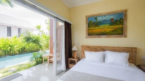 A hotel room with a bed, a painting, a view of a swimming pool, and a door leading to an outdoor area with plants. - Sujiwa Ubud Retreat (Sukawati)
