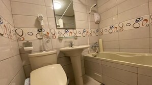 Ένα μπάνιο με τουαλέτα, νιπτήρα και μπανιέρα.