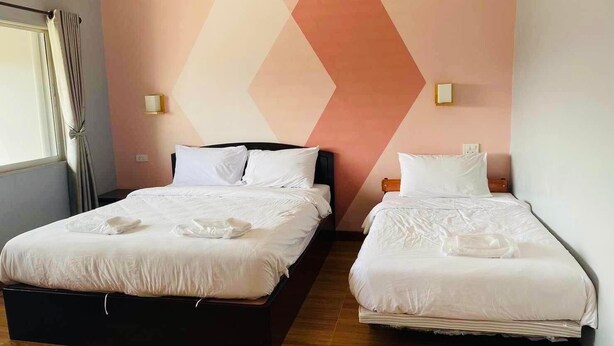 A hotel room with two beds, a wooden floor, and a geometric wall design. - Mest Hotel (Phatthalung)