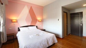 A hotel room with a bed, two wall-mounted lamps, a dark door, and a tiled floor. - Mest Hotel (Phatthalung)
