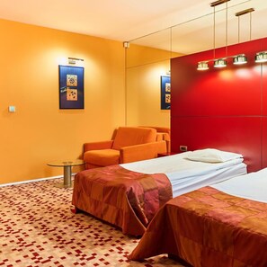 A hotel room with two beds, an orange armchair, a small table, and a red wardrobe. - Mirena Hotel (Plovdiv)
