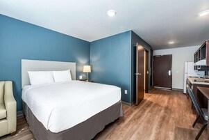 Una habitación de hotel con una cama grande, un escritorio, una silla y un armario.