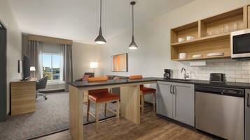 A modern kitchen with a central island, bar stools, a microwave, and a dishwasher.