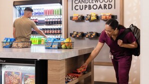 A self-service beverage station with a refrigerated drink cooler and a display of snacks and packaged foods. - Woodspring Suites Pecos (Pecos)