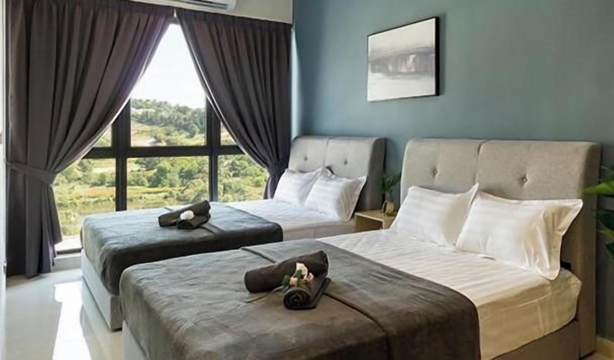 A hotel room with two beds, a large window, and a view of greenery.