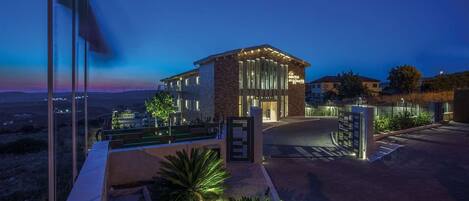 A modern hotel with a prominent entrance, a landscaped driveway, and a view of the surrounding landscape.