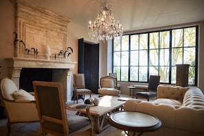 A spacious living room with a fireplace, comfortable seating, and large windows. - Domaine de Fontenille (Lauris)