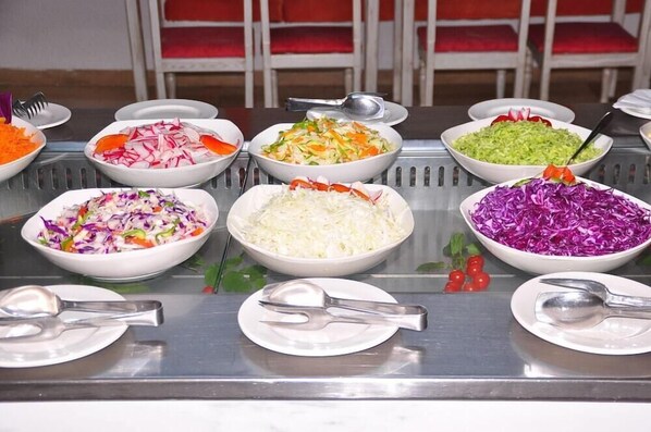 Egy svédasztal, melyen különféle ételek találhatók, többek között káposztasaláta, reszelt káposzta és vegyes zöldségek.