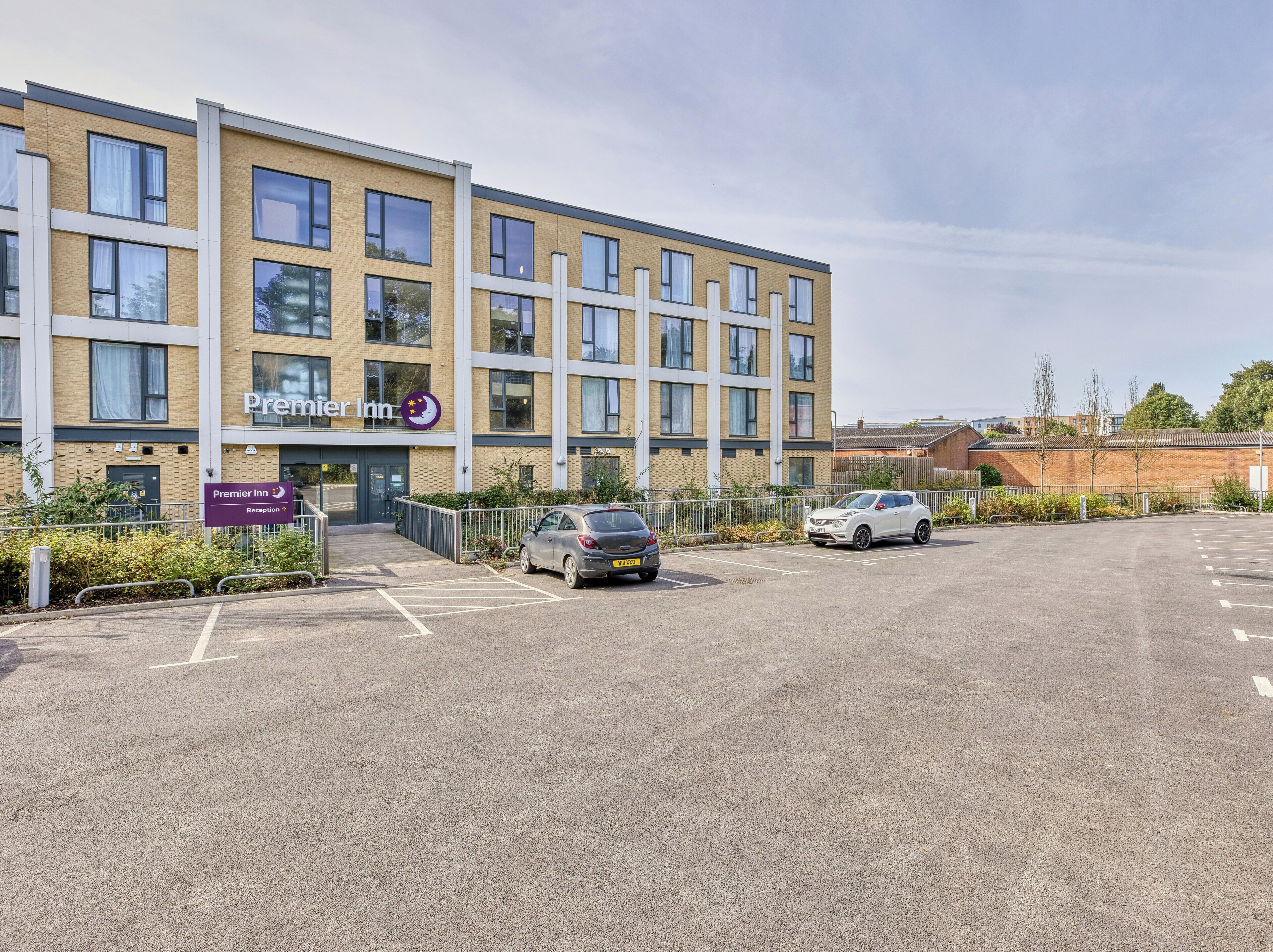 A hotel with a reception area, parking lot, and a building facade with windows and signage.