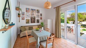Un comedor acogedor con una mesa dispuesta para dos, un sofá y un ventanal con vistas a zonas verdes.