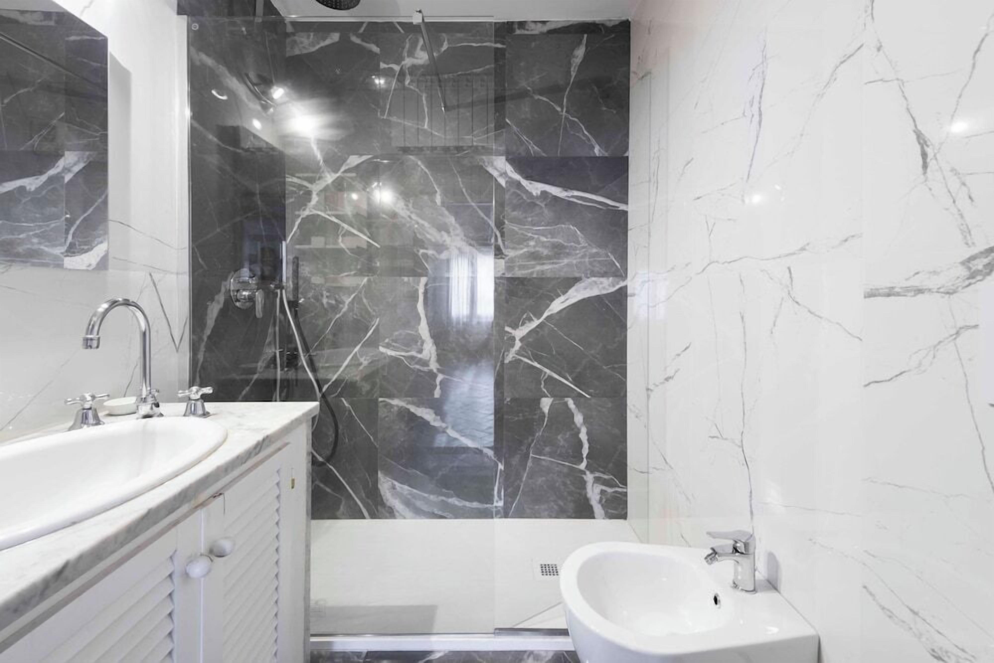 A modern bathroom with a large mirror, a bathtub, and a separate sink.