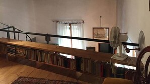 Un loft spacieux avec des poutres apparentes, un escalier en bois et une bibliothèque remplie de livres.
