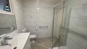 Ein modernes Badezimmer mit Duschkabine aus Glas, einem weißen Waschbecken und einer Toilette.