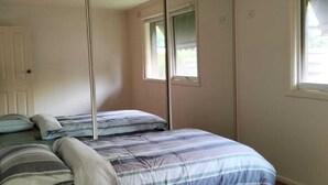 Ein Schlafzimmer mit einem Bett, einem Spiegel und einem Fenster.