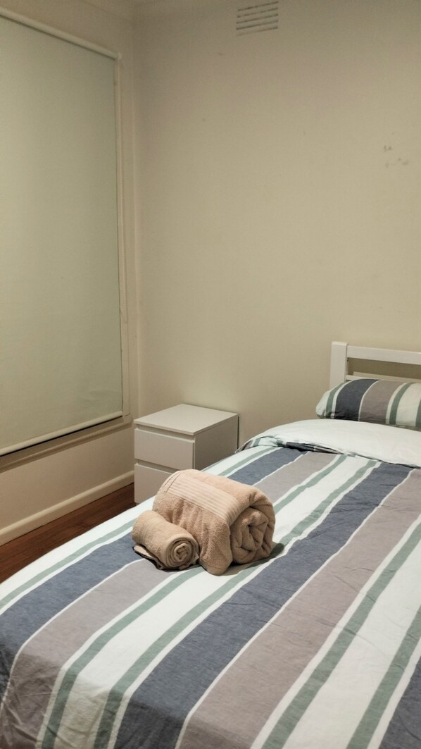 Un dormitorio con cama, mesita de noche y ventana.
