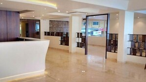 A modern hotel lobby with a curved reception desk, a patterned wall, and a view of the street through a glass door. - Cosmique Clarks Inn Suites Goa (Margao)