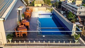 A rooftop swimming pool with a seating area and a view of the surrounding buildings. - Cosmique Clarks Inn Suites Goa (Margao)