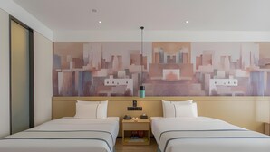 A hotel room with two beds, a large abstract painting on the wall, a bedside table with a lamp, and a wooden floor. - City Comfort Inn Kunming Railway Station (Kunming)